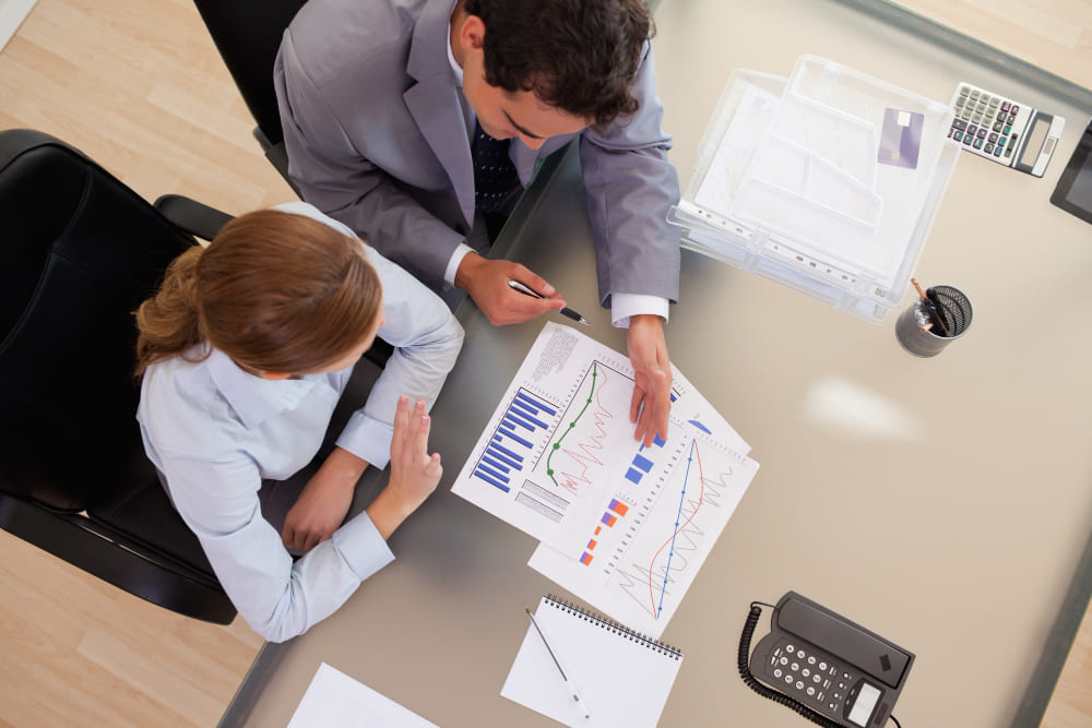 Мужчина и женщина обсуждают графики и финансовые показатели за офисным столом