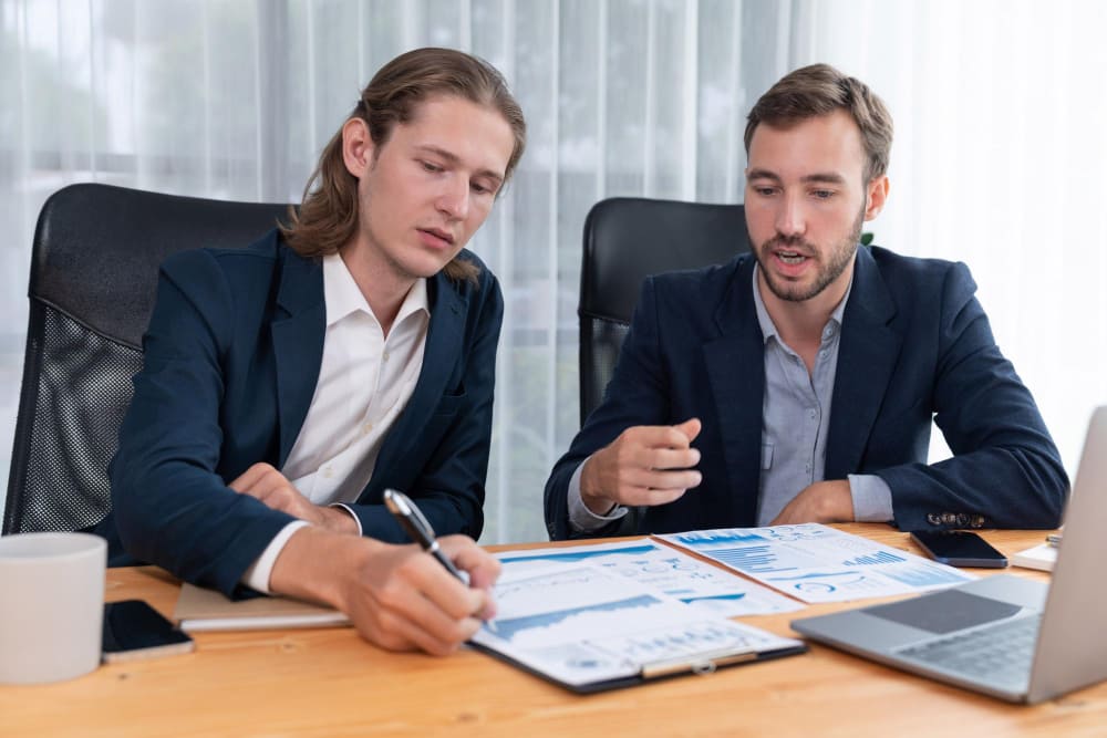 Два бизнесмена обсуждают инвестиционную стратегию, анализируя графики и финансовые показатели
