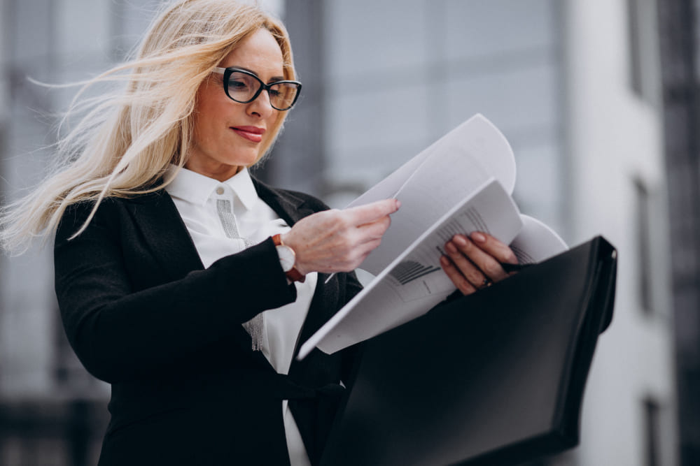 Профессиональная женщина с очками изучает юридические документы на фоне современного здания