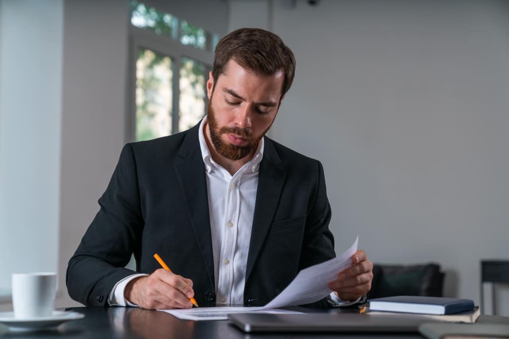 Мужчина в костюме внимательно проверяет юридические документы